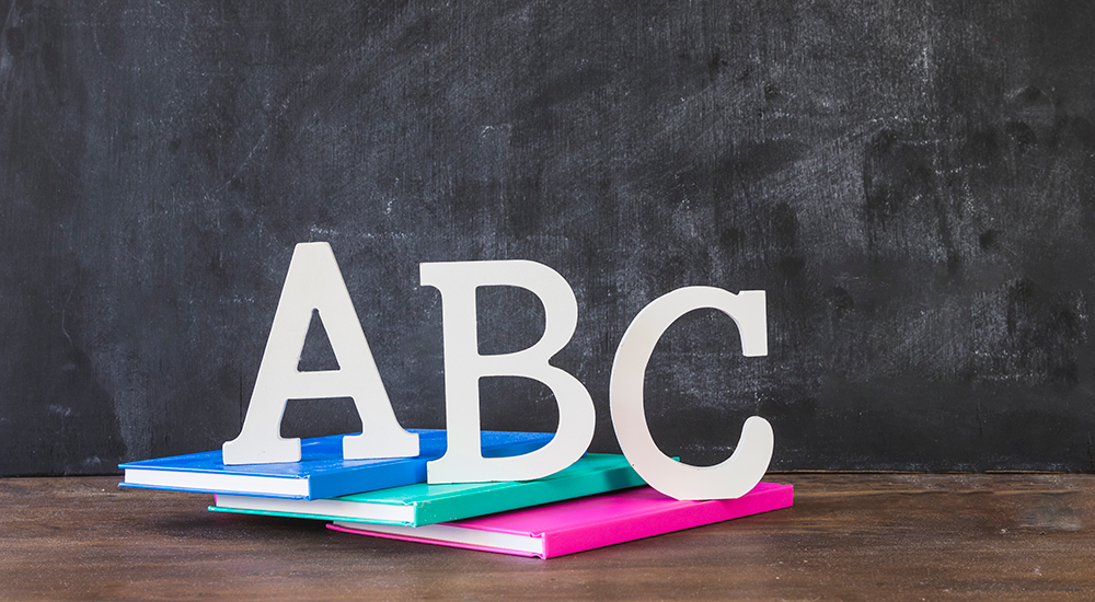 desktop-with-abc-letters-books-near-chalkboard